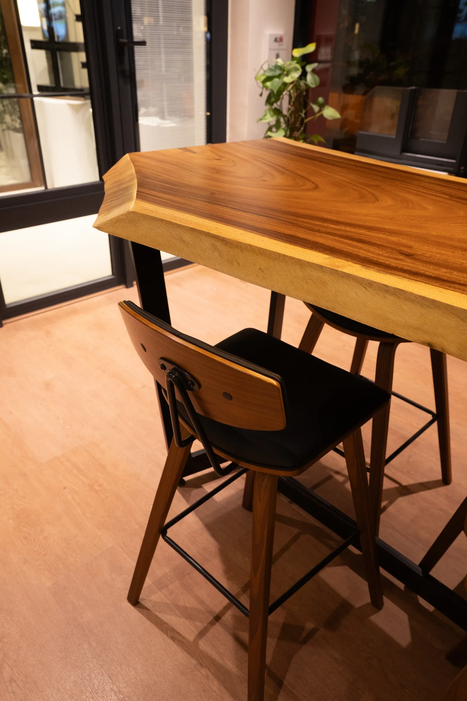 Live-edge timber table with black chairs — Aluk Experience Center